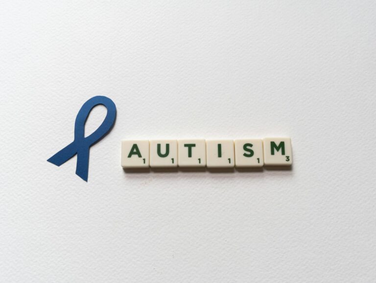 Blue ribbon and autism spelled with letter tiles symbolize autism awareness.