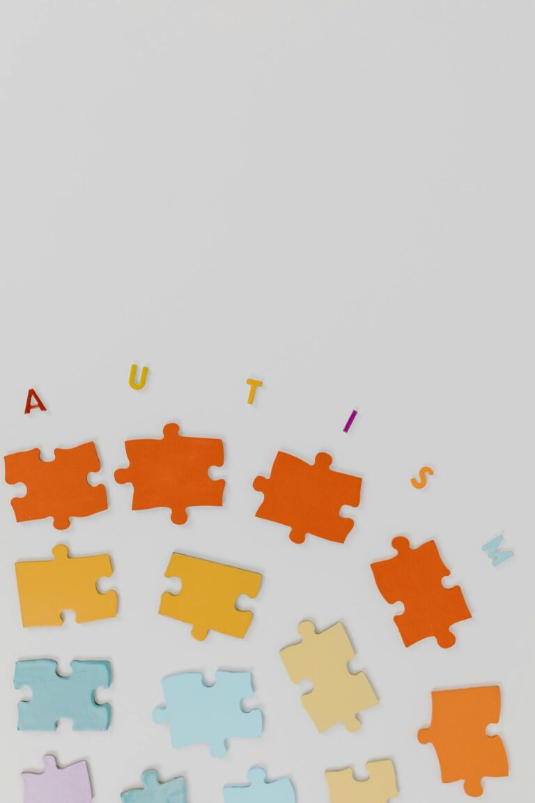 Colorful puzzle pieces and letters forming the word 'AUTISM' on a white backdrop.