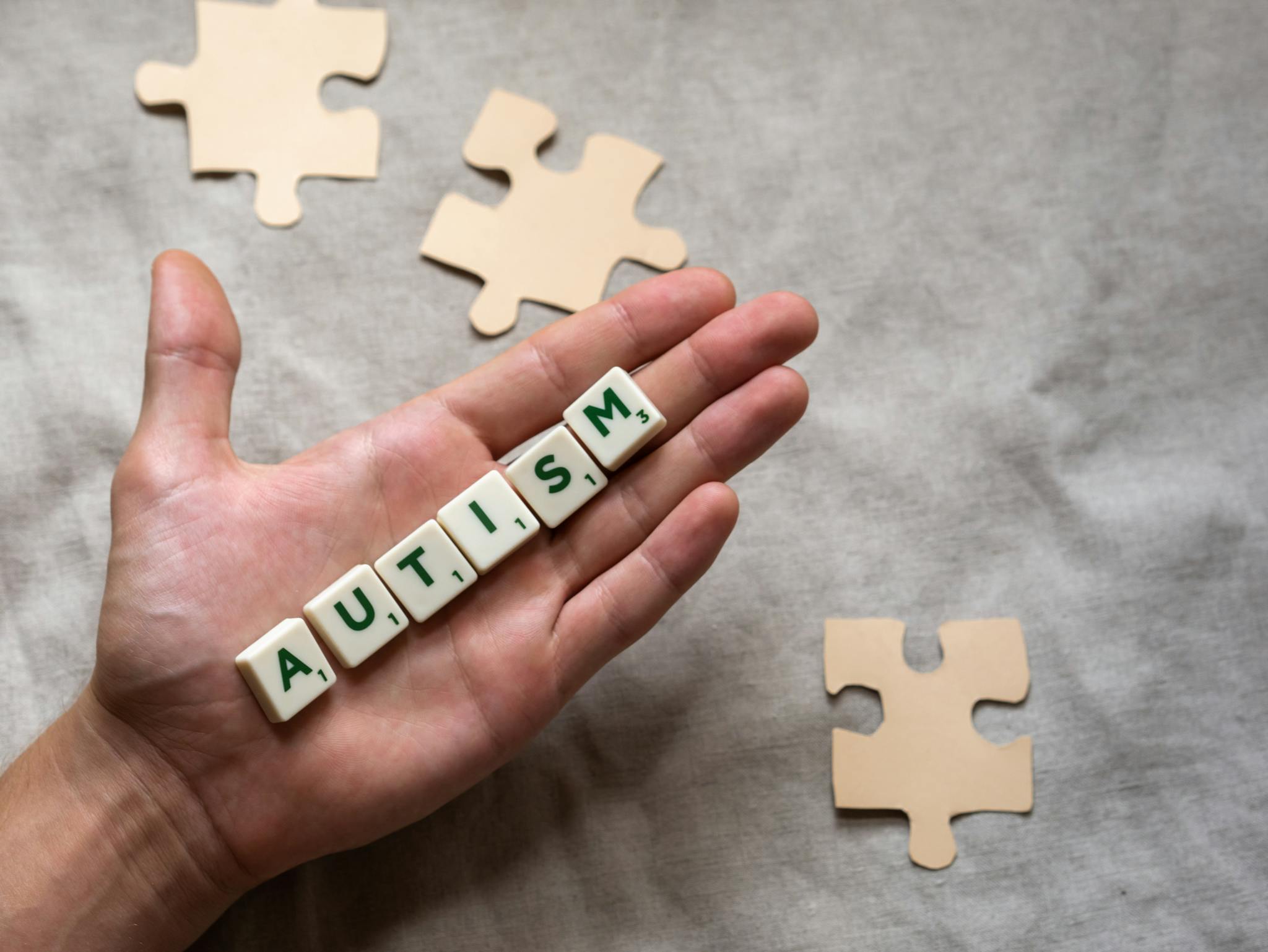 Hand Displaying Autism Spelled With Scrabble Tiles
